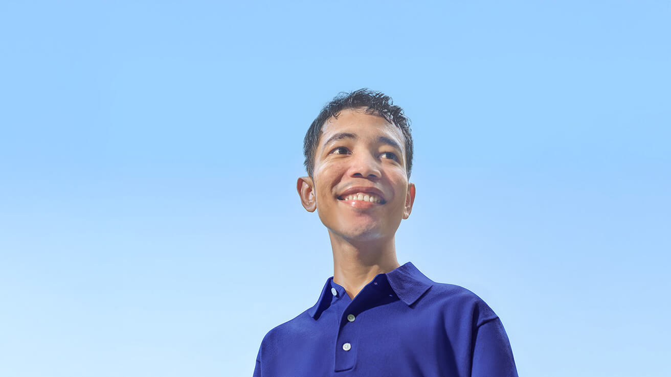 Photograph of an individual featured in a patient story, standing on an indoor sports